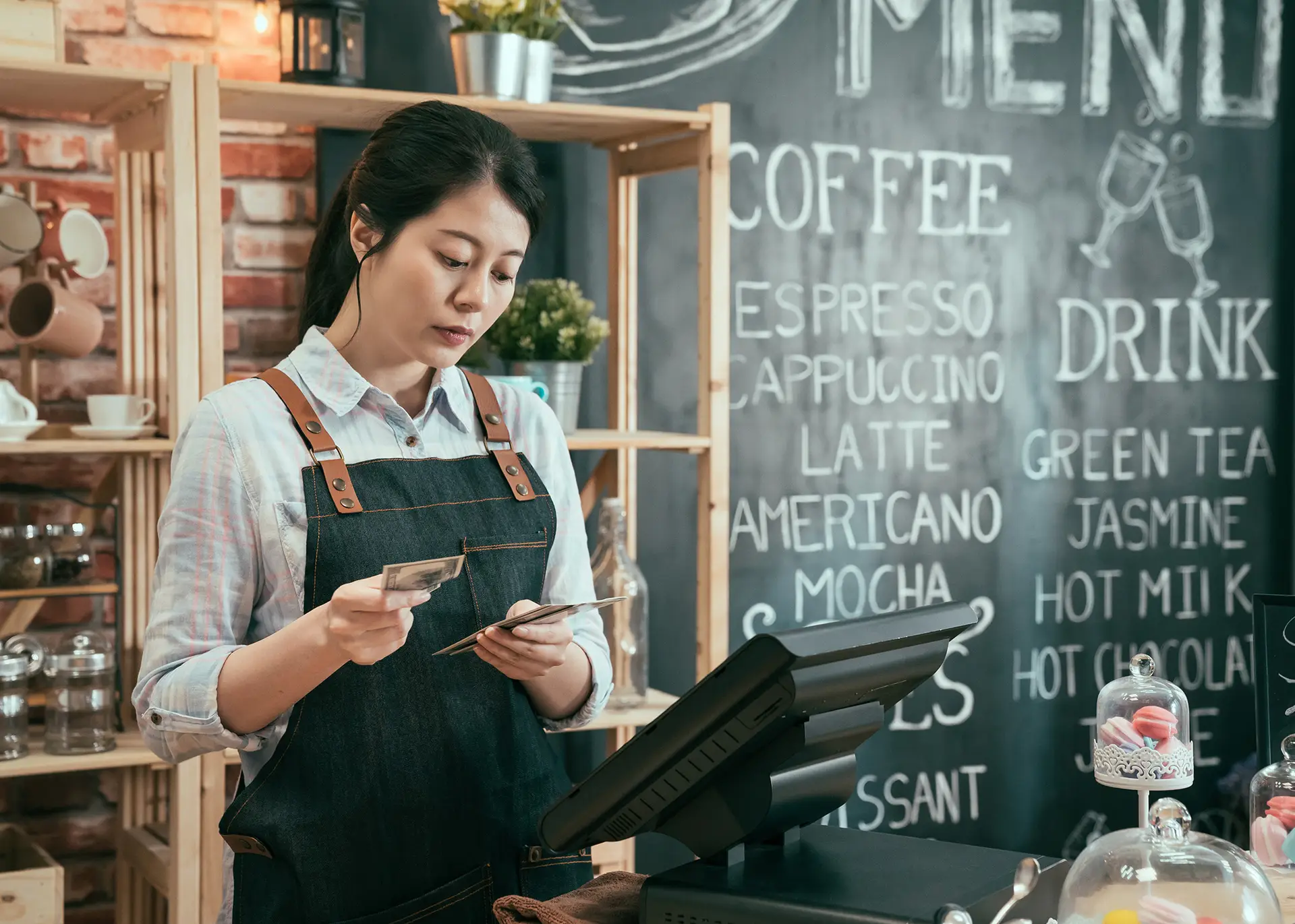 cafe employee manually counting cash at till looking frustrated